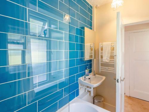 キリミュアにある3 bed in Kirriemuir 82244の青いタイル張りのバスルーム(バスタブ、シンク付)