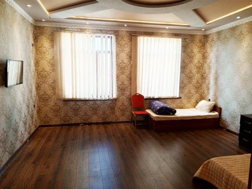 a bedroom with a bed and a chair and windows at Temur Hotel in Dushanbe