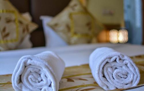 two rolled towels sitting on top of a bed at Hotel Crystal Inn Plaza Delhi Airport in New Delhi