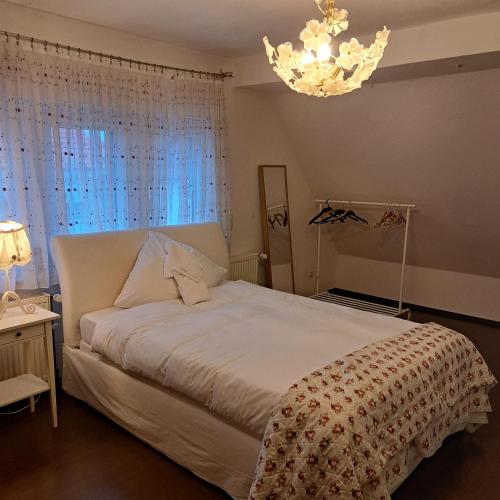 a bedroom with a white bed and a chandelier at Messe Zimmer Hannover in Hannover