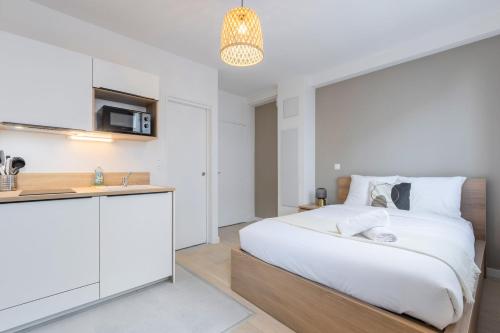 Cet appartement comprend une chambre avec un lit blanc et une cuisine. dans l'établissement Lille Saint-Michel Fully-equipped studio, à Lille