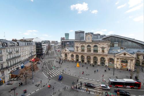 une rue urbaine animée avec un grand bâtiment et des bus dans l'établissement Apartment for 4 in front of Lille Flandres station, à Lille