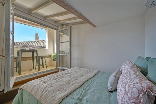 une chambre avec un lit et une grande fenêtre dans l'établissement Les toits des PAPES - Clim - WIFI - AVIGNON, à Avignon