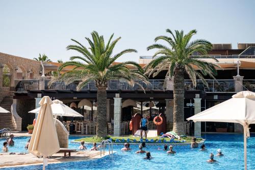 a group of people in a swimming pool with palm trees at Caldera Creta Paradise in Plataniás