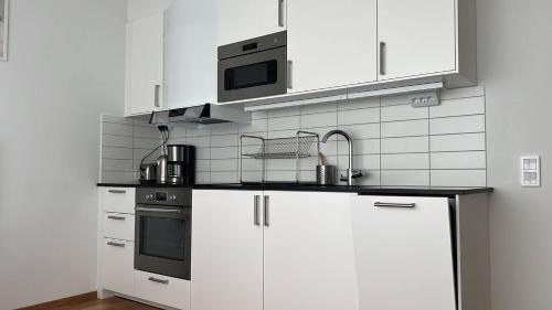 La cuisine est équipée de placards blancs et d'un four micro-ondes. dans l'établissement Private Terrace Apartment, à Göteborg