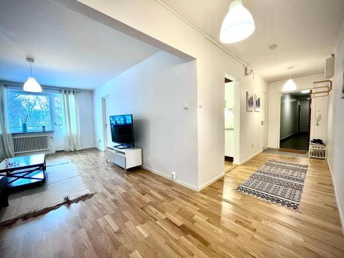 uma grande sala de estar com televisão e piso de madeira em Elegant Apartment In Lovely Location em Gotemburgo