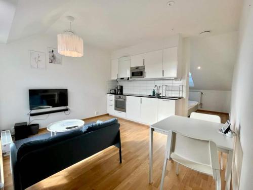 a living room with a table and a white kitchen at Cozy Private Terrace Flat In Central Gothenburg in Gothenburg