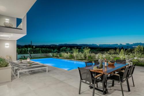 a patio with a table and chairs and a swimming pool at AKEA VILLAS in Tragaki