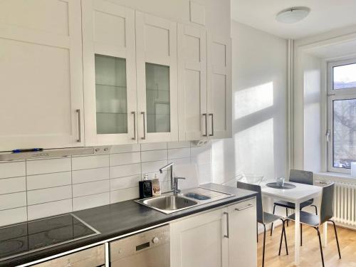 a kitchen with white cabinets and a sink and a table at Luxury Apartment In City Centre in Gothenburg