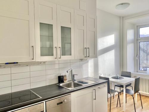 a kitchen with white cabinets and a sink and a table at Luxury Apartment In City Centre in Gothenburg
