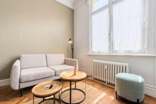 een woonkamer met een bank en 2 tafels bij Charming and comfortable apartment near tramway in Marcq-en-Baroeul