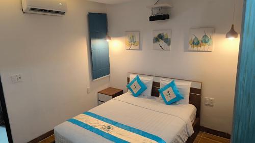 a bedroom with a bed with blue pillows at FLORA Hotel Phu Quoc in Phu Quoc