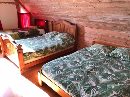 2 Betten in einem Zimmer mit Holzwänden in der Unterkunft Grand gîte familial in Ploumagoar