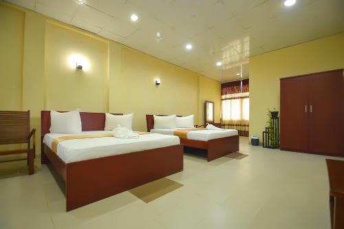 a hotel room with two beds in a room at Gunners Club in Minneriya