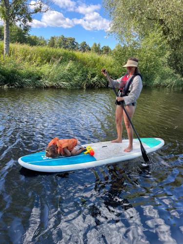 a woman and a dog on a paddle board in the water at Gangvidefarm in Stånga
