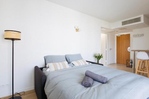 a white bedroom with a large bed with purple pillows at Magnifique 2 pièces avec terrasse, Paris La Défense in Courbevoie