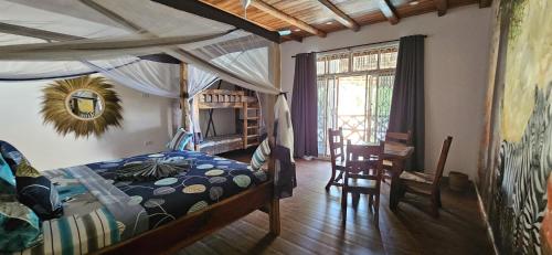 a bedroom with a canopy bed and a table and chairs at Waka Waka in Pwani Mchangani
