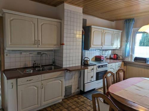 a kitchen with white cabinets and a table and a sink at Ferienhaus Brigitte in Dichtelbach