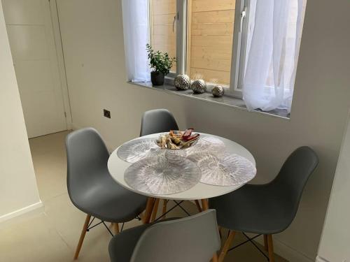 una mesa con cuatro sillas y un bol de fruta en ella en Annex D. One Bedroom flat in south London, en Carshalton