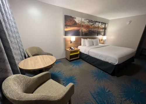 a hotel room with a bed and two chairs at Days Inn by Wyndham Valdosta I-75 in Valdosta