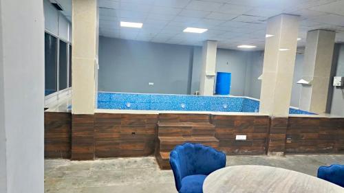 um quarto com uma piscina com paredes e cadeiras azuis em Farm with 5 huts, heated pool and bonfire em Gurgaon