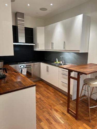 eine Küche mit weißen Schränken und einem Holztisch in der Unterkunft Luxury Apartment In City Hotspot in Göteborg