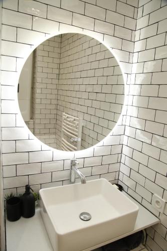 une salle de bain blanche avec un lavabo et un miroir dans l'établissement Apparemment cosy île saint louis, à Paris