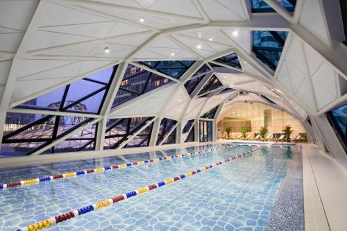 a large swimming pool in a building with a large ceiling at Ascott Raffles City Beijing in Beijing