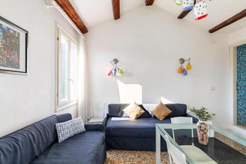 威尼斯的住宿－iHOMES Rialto-Corte del Calice-Attico vista centro，客厅配有蓝色的沙发和玻璃桌