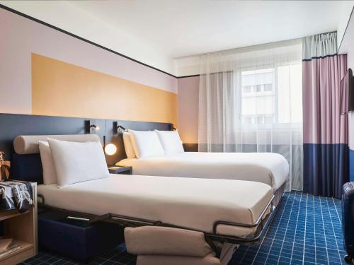 a hotel room with two beds and a window at Mercure Paris 15 Porte de Versailles in Paris