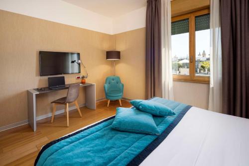 a bedroom with a bed and a desk with a television at Best Western Plus City Hotel in Genoa