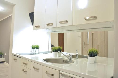 a white kitchen with a sink and a mirror at Nice and comfy studio close to Old town and metro. in Warsaw