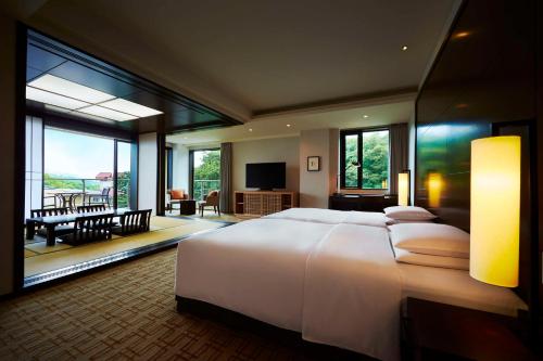 a bedroom with a large white bed and a living room at Hyatt Regency Hakone Resort and Spa in Hakone