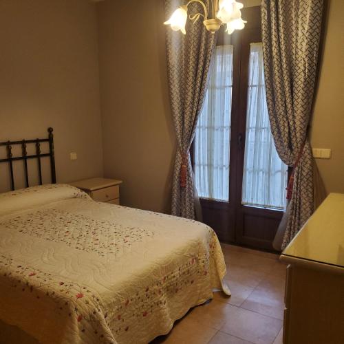 um quarto com uma cama e uma janela com cortinas em VUT Casa abuela Antonia em El Barco de Ávila