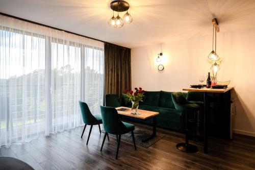 a living room with a green couch and a table at Apartament w Winiarni in Dąbrówka Szczepanowska