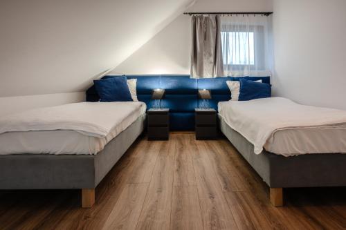 two beds in a room with blue walls and wooden floors at Apartament w Winiarni in Dąbrówka Szczepanowska