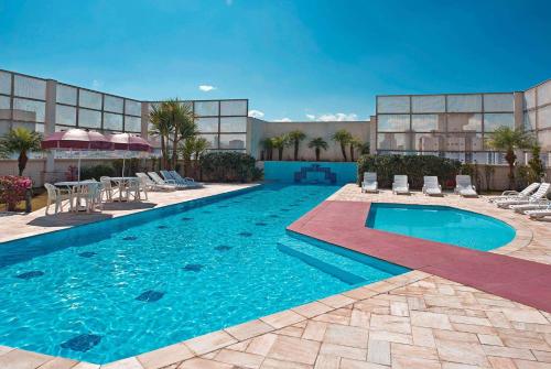 a swimming pool with chairs and a table and a building at Wyndham Garden São Paulo Convention Nortel in Sao Paulo