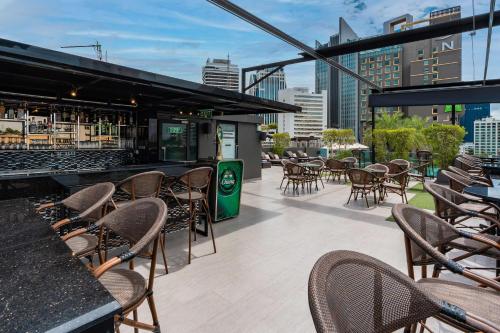 eine Terrasse mit Tischen und Stühlen sowie eine Bar in der Unterkunft SureStay Plus by Best Western Sukhumvit 2 in Bangkok