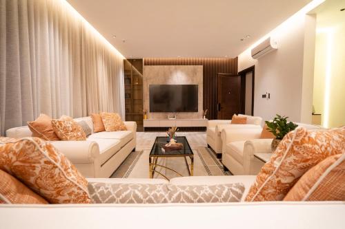 Riyadh Comfort Stay - Luxury الملقا Almalqa, 3 Bedrooms في الرياض: غرفة معيشة مع أرائك بيضاء وتلفزيون بشاشة مسطحة