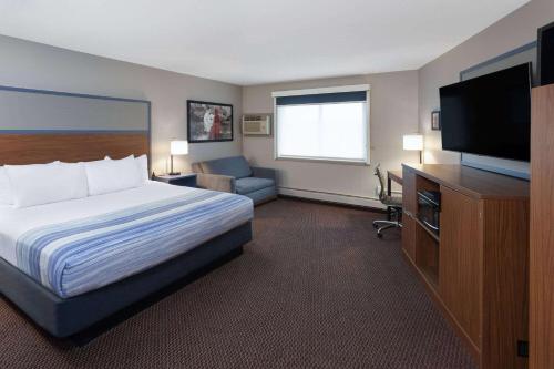 a hotel room with a bed and a flat screen tv at AmericInn by Wyndham New Richmond in New Richmond