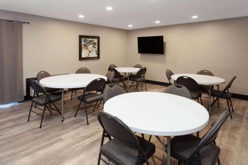 a room with tables and chairs and a flat screen tv at AmericInn by Wyndham New Richmond in New Richmond