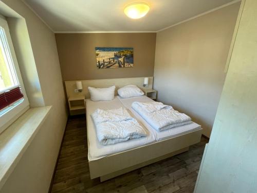 a small bedroom with a bed with white blankets and pillows at Küstenbrise 2 in Graal-Müritz
