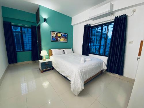 a bedroom with a bed and blue walls and windows at Amazing Apartment in Bashundhara in Dhaka