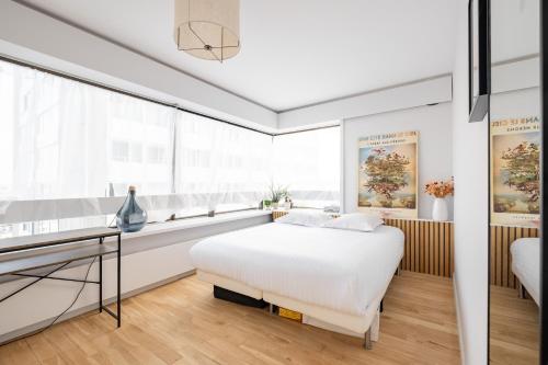 une chambre blanche avec un lit et un bureau dans l'établissement Veeve - Riverside Heights, à Paris