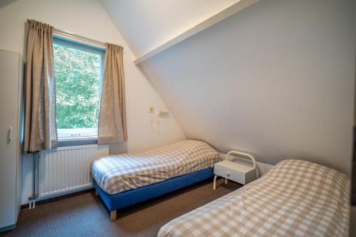 a room with two beds and a window at Nieuwlanderweg 51 in De Waal
