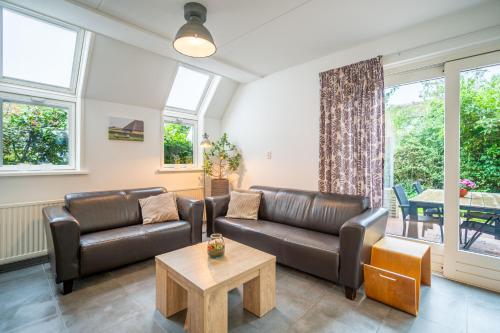 a living room with leather furniture and a table at Nieuwlanderweg 51 in De Waal
