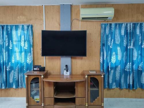 a flat screen tv on a wooden wall with curtains at Comfort Stay Kuala Perlis Wi-Fi Nexflix in Kuala Perlis