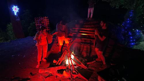 a group of people walking around a fire at night at Casspo bunk bed in Devikolam