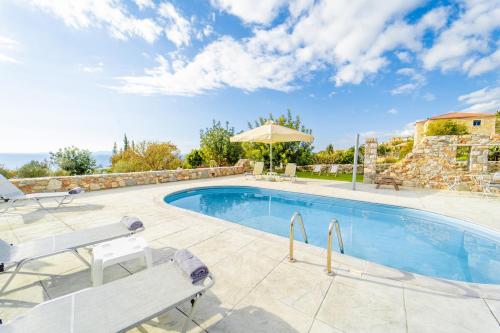 a swimming pool with chairs and an umbrella at Villa Dioni Tria in Pírgos