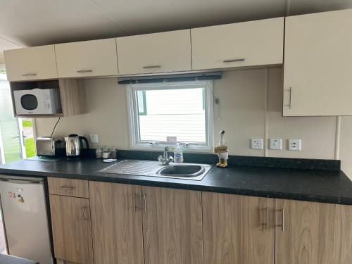 a kitchen with a sink and a window at McCanns Caravan Marton Mere in Blackpool
